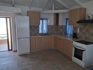 a kitchen with white appliances and wooden cabinets at Makri Guest House in Livanates +4 photos