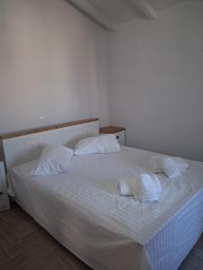a bed with white sheets and pillows on it at Makri Guest House in Livanates