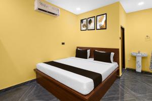 a bedroom with a large bed in a yellow wall at Hotel O Shadnagar Formerly Sri Jogulamba Residency in Bālānagar