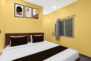 a bedroom with a bed with yellow walls and a window at Hotel O Shadnagar Formerly Sri Jogulamba Residency in Bālānagar +22 photos
