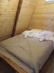 a bed in a wooden room with white sheets and pillows at A-frame с видом на горы in Kokotauri