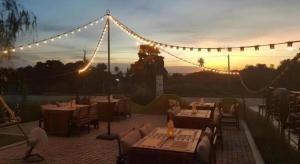 a restaurant with tables and chairs and a string of lights at Chaisaeng Villa in Sing Buri