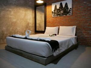 a large bed in a room with a brick wall at 41Studio in Nakhon Phanom