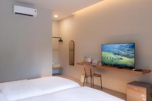 a bedroom with a bed and a tv on a wall at The Cozy Hotel in Phetchaburi
