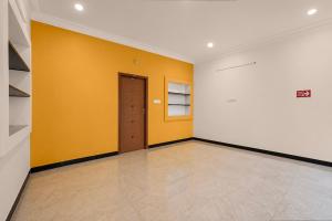 an empty room with yellow and white walls and a door at Collection O Anbu Nagar Coimbatore in Coimbatore