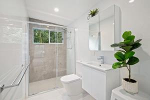 a white bathroom with a toilet and a shower at The Palm Cabin 2 in Mylestom