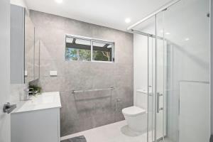 a bathroom with a shower and a toilet and a sink at The Palm Cabin 2 in Mylestom