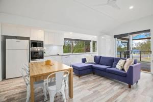 a living room with a blue couch and a table at The Palm Cabin 2 in Mylestom +19 photos