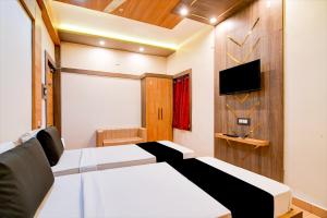 a bedroom with two beds and a flat screen tv at Hotel Shree Krishna in Keonjhargarh