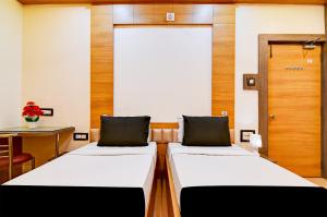 two beds in a room with a desk and a table at Hotel Shree Krishna in Keonjhargarh