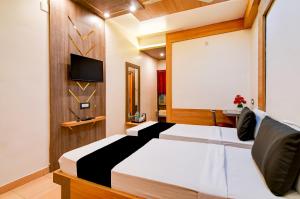 a bedroom with two beds and a flat screen tv at Hotel Shree Krishna in Keonjhargarh +46 photos