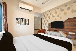 a bedroom with a white bed and a flat screen tv at Hotel O Sabarmati Ashram Ahmedabad Formerly Red Apple in Ahmedabad