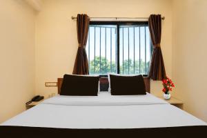 a bedroom with a large bed with a window at Hotel O Sabarmati Ashram Ahmedabad Formerly Red Apple in Ahmedabad