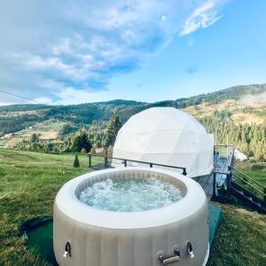 a hot tub in the middle of a field at WildGlampingArieseni in Arieşeni