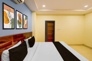 a bedroom with a white bed and paintings on the wall at Super Hotel O AMR Planet Mall Hyderabad Formerly R Square in Maula Ali +23 photos