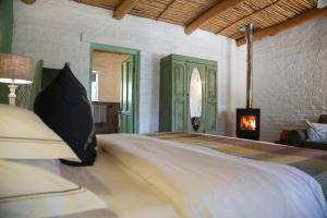 a bedroom with a bed with a fireplace in it at Dennehof Karoo Guesthouse in Prince Albert