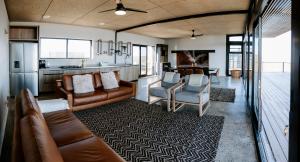 a living room with leather furniture and a kitchen at Oudeberg Living- Oudeberg Lodge in Sutherland