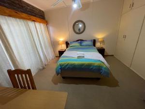 a bedroom with a bed and a table in it at Eagle Waters in Vanderkloof
