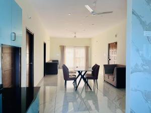 a dining room and living room with a table and chairs at Selfie Residency in Mysore