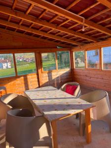 a wooden table and chairs in a room with windows at Vidovdanska house in Šipovo