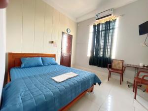 a bedroom with a blue bed and a desk at ANH VAN Motel in Chau Doc +3 photos