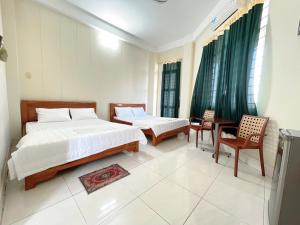 a bedroom with two beds and a table and chairs at ANH VAN Motel in Chau Doc