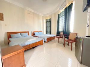 a bedroom with two beds and a table and chairs at ANH VAN Motel in Chau Doc