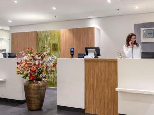 a woman talking on a phone at a reception desk at Mercure Hotel Schiphol Terminal in Schiphol