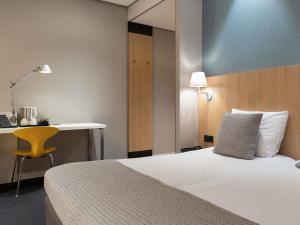 a hotel room with a bed and a desk and a chair at Mercure Hotel Schiphol Terminal in Schiphol