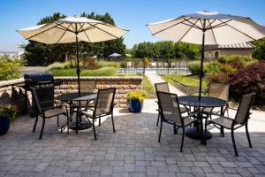 two tables and chairs with umbrellas on a patio at Hampton Inn Dover in Dover