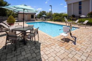 a table with chairs and an umbrella next to a pool at Hampton Inn Dover in Dover
