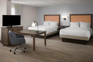 a hotel room with two beds and a desk and a television at Hampton Inn Dover in Dover