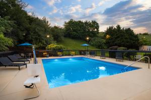 a swimming pool on a patio with chairs and umbrellas at Hampton Inn Staunton in Staunton