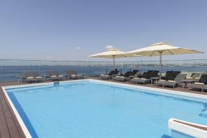 a swimming pool with chairs and umbrellas on a building at DoubleTree By Hilton Istanbul - Moda in Istanbul
