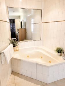 a white bathroom with a tub and a mirror at Peninsula Motor Inn in Tyabb +11 photos