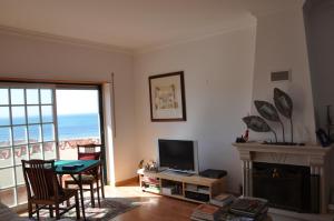 - un salon avec une table, une télévision et une cheminée dans l'établissement Ericeira Beach Place, à Ericeira