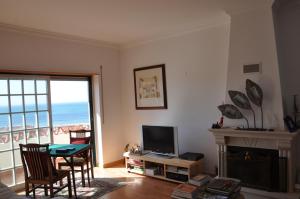 a living room with a table and a television and a fireplace at Ericeira Beach Place in Ericeira