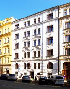 biały budynek z zaparkowanymi przed nim samochodami w obiekcie Hotel Olga w Pradze