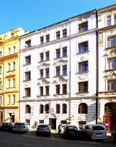 a white building with cars parked in front of it at Hotel Olga in Prague