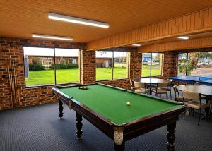 a room with a pool table and tables and windows at Peninsula Motor Inn in Tyabb