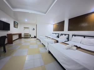 a room with four beds and a desk in it at White Beach Resort Bar & Restaurant in Puerto Galera
