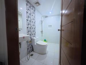 a white bathroom with a toilet and a sink at White Beach Resort Bar & Restaurant in Puerto Galera +32 photos