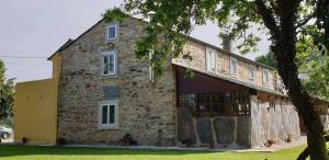 a large stone building with a tree in front of it at A Casa da Zalaroia, para amantes de la naturaleza in San Mamed