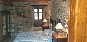 a bedroom with a bed and a stone wall at A Casa da Zalaroia, para amantes de la naturaleza in San Mamed