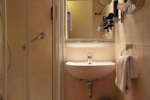 a bathroom with a sink and a shower with a mirror at TOP Hotel Amberger in Würzburg