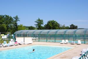 a person swimming in a swimming pool with a building at Cottages du Lac de Miel in Beynat