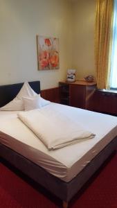 a bed in a room with a white bedsheet at TOP Hotel Amberger in Würzburg