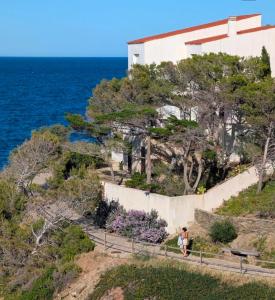 a person walking up a retaining wall next to the ocean at Emporda Llanca Guesthouse in Llança