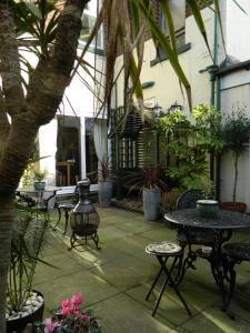 卡莱尔Abbey Court Guest House的一个带桌椅和盆栽的庭院