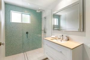 a bathroom with a shower and a sink and a mirror at Pacific Waves Apartments in Noosa Heads
